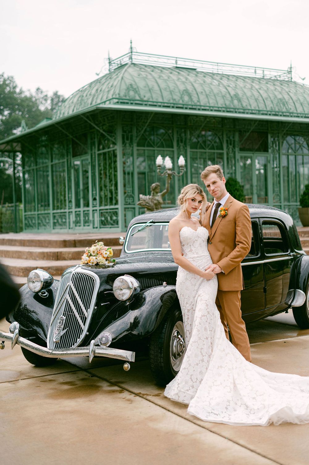 Classic black vintage Citroen car parked in front of a Victorian style greenhouse pavilion at an elegant wedding.