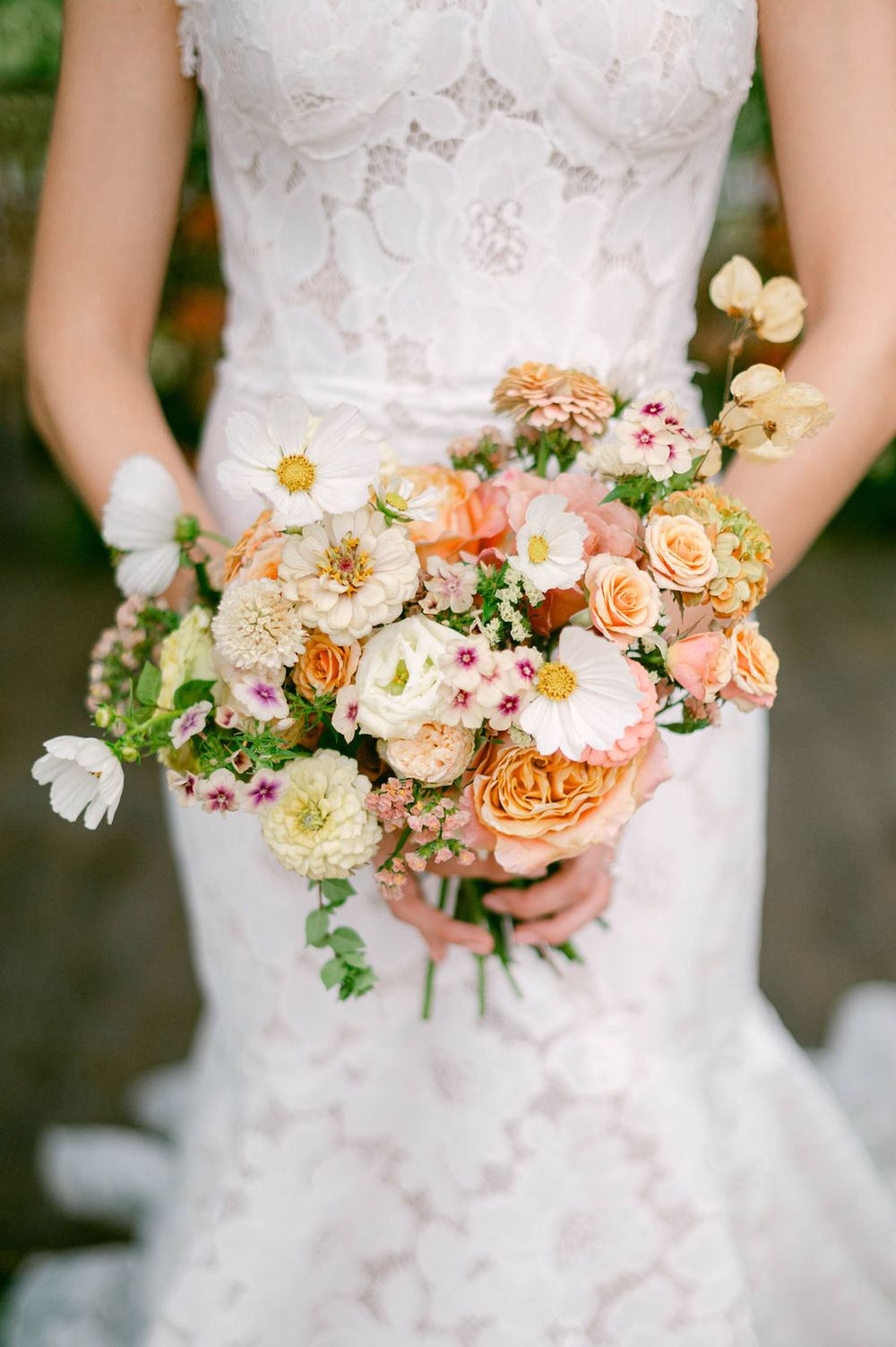 Close-up views of peach and coral wedding bouquets with roses and mixed flowers against white lace dresses.