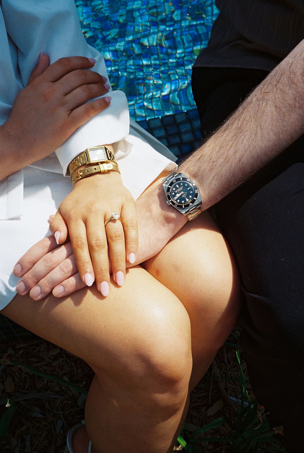 Sequence of hands tenderly holding another person's knee in warm sunlight against a blue mosaic background.