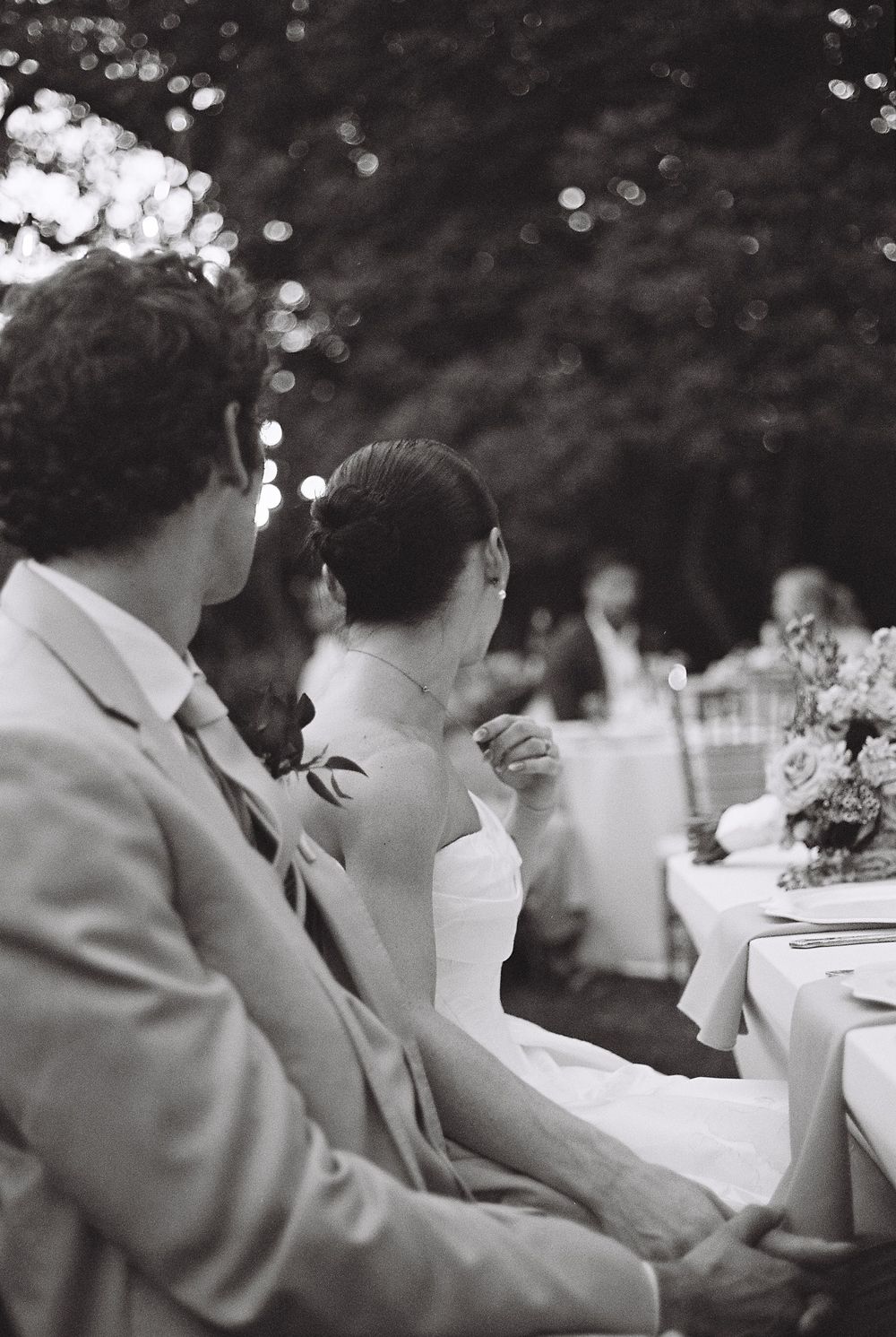A series of black and white candid images showing guests seated at an outdoor reception venue.