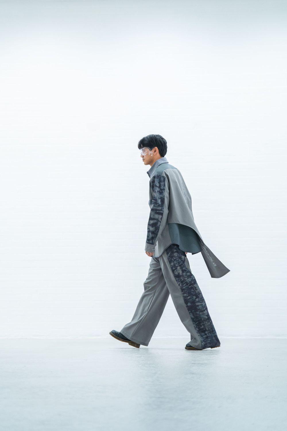 Artistic fashion photo series showing model in flowing gray overcoat against white background.