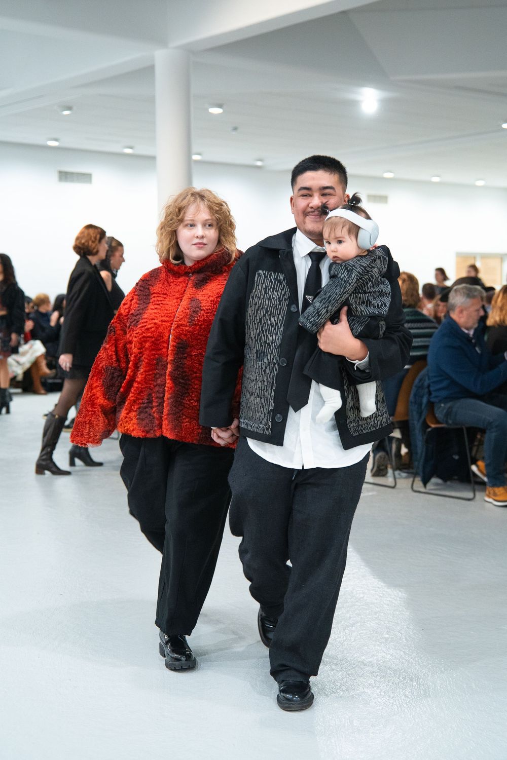 Fashion show featuring models in black ensembles with bright red accessories.