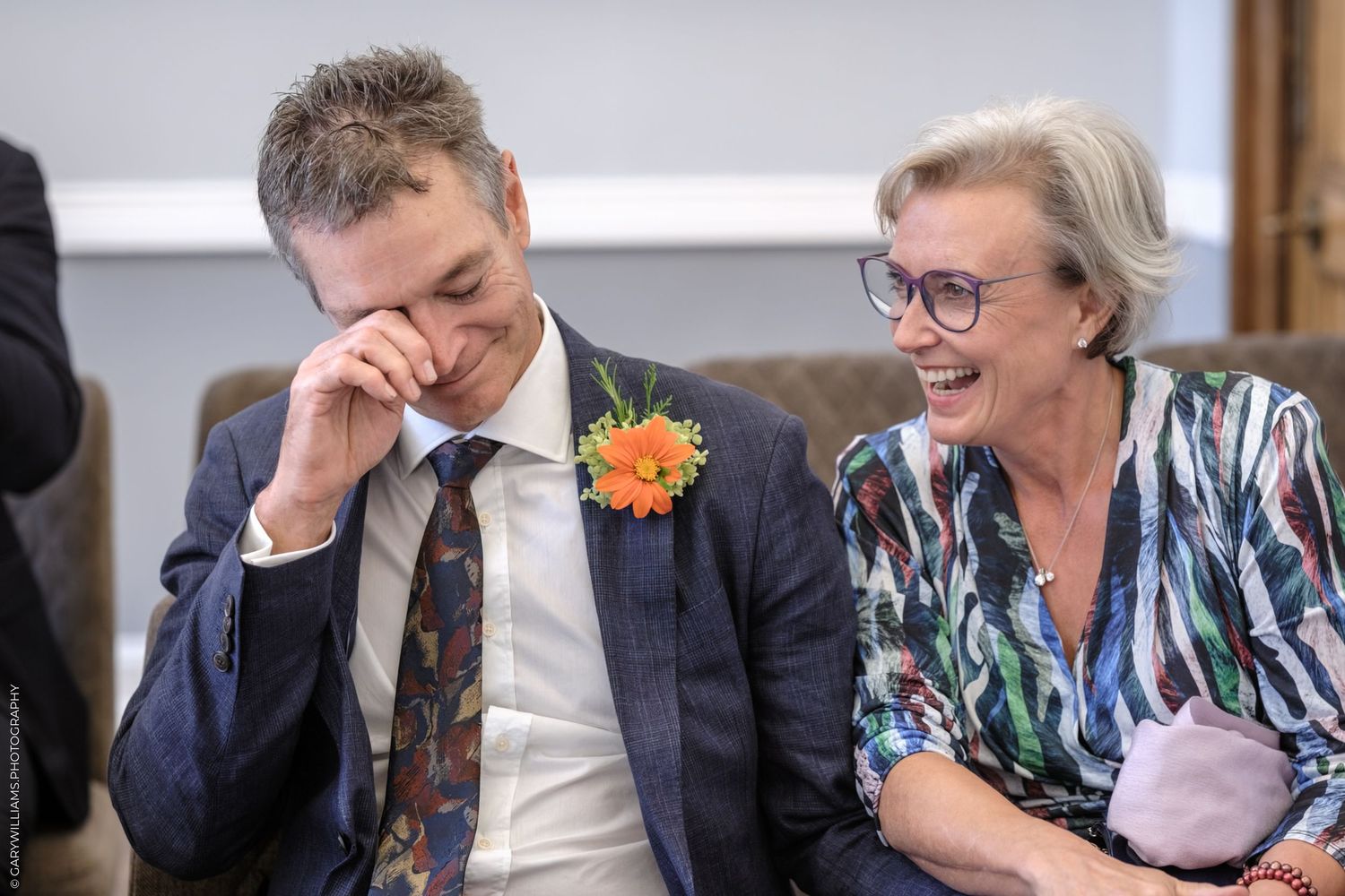 Wedding party members interact and smile during a candid moment at a reception.