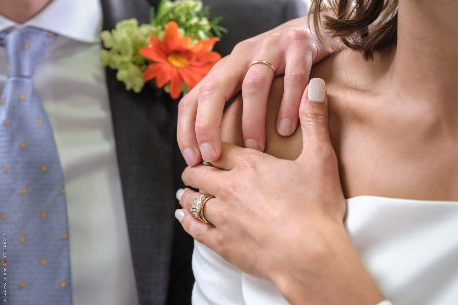 Person wearing a white wedding dress holding a delicate rose flower during a romantic moment.
