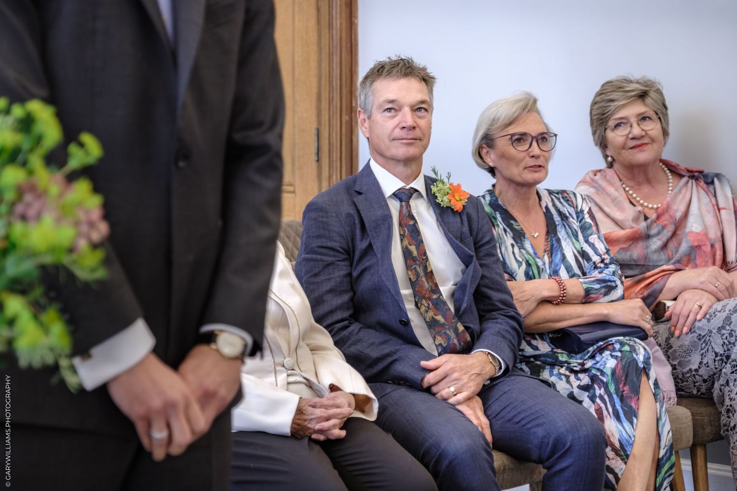 Wedding guests seated in formal attire watching ceremony proceedings.