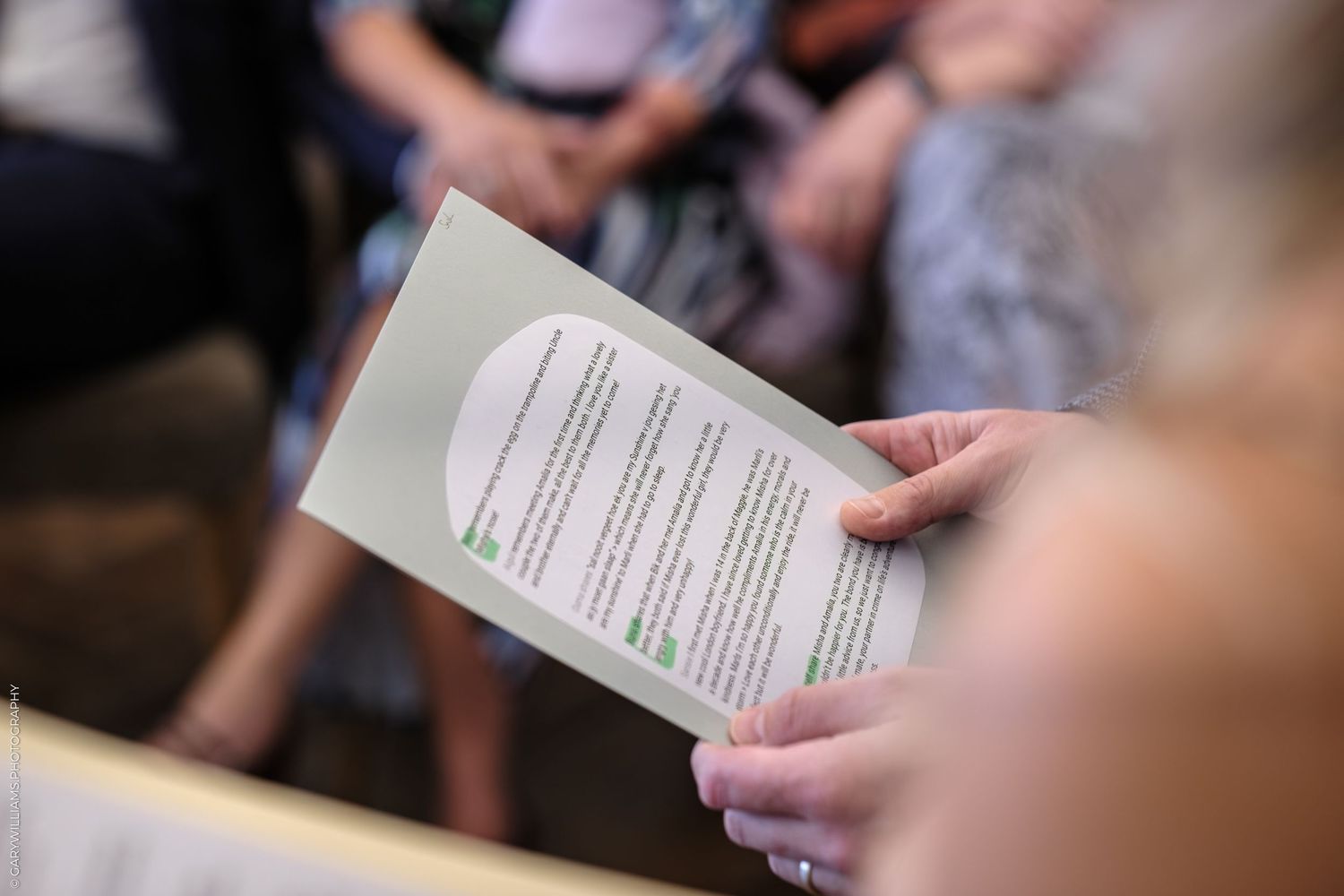 Multiple hands holding printed ceremony programs during a wedding service.