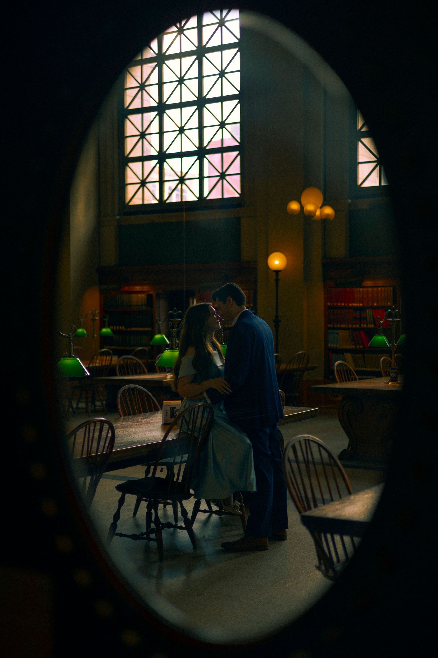 Dark room with vintage windows and tables illuminated by warm lighting creates a moody, atmospheric setting in a dining space.