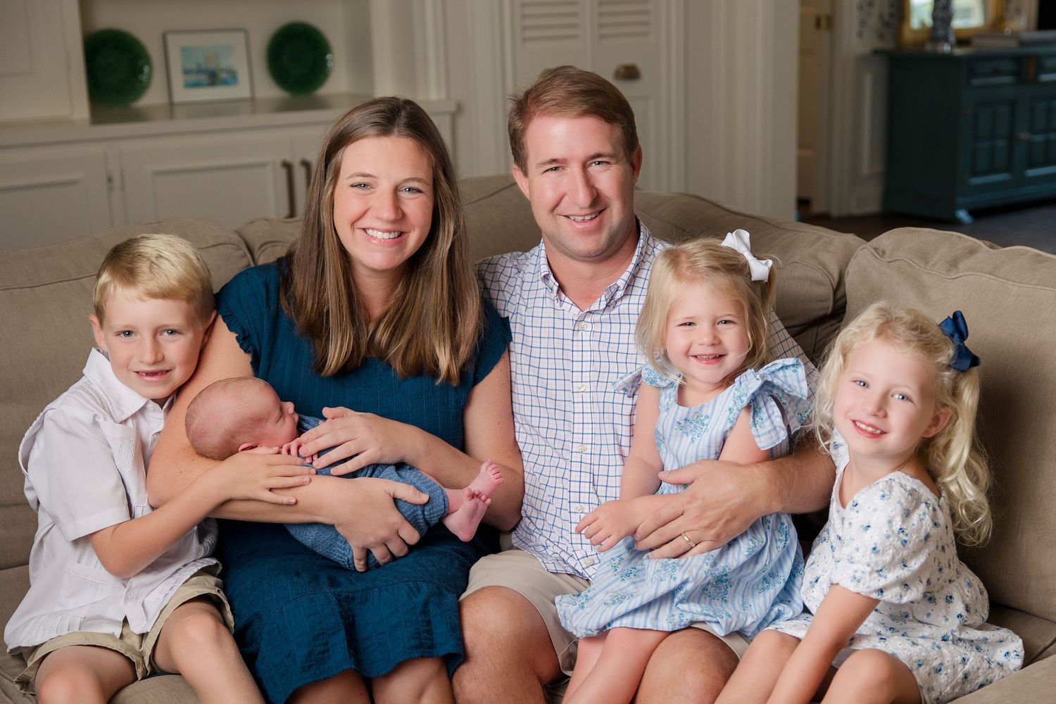 A loving family relaxes together for professional portraits in coordinating blue and white outfits.