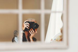 Close-up view of someone taking a photo reflected in a window pane.