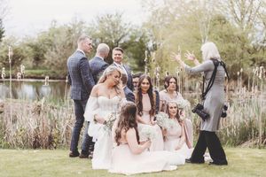 Wedding party stands together in elegant poses at an outdoor garden venue against a natural backdrop.