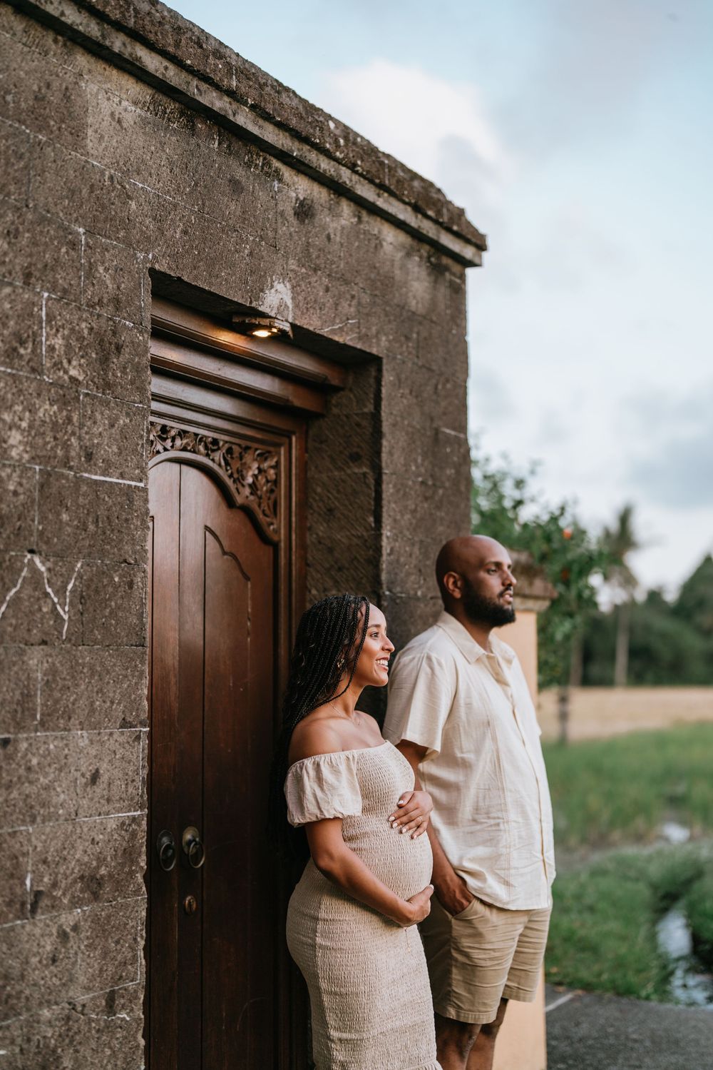 Couple poses against stone wall with wooden doors for romantic outdoor portraits.