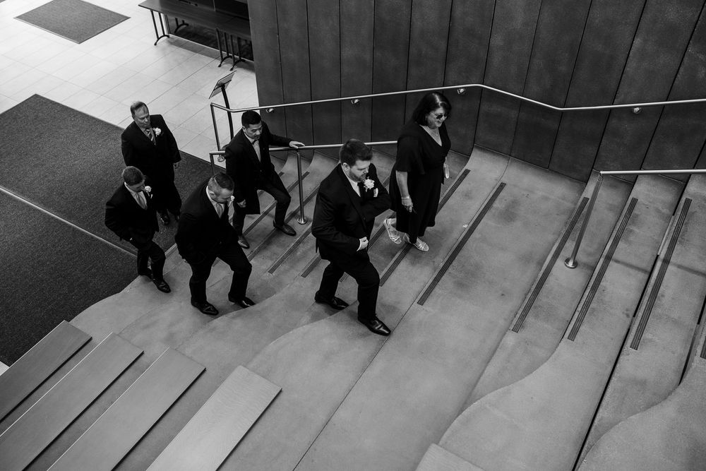 Black and white overhead view of people descending concrete stairs in an urban setting.