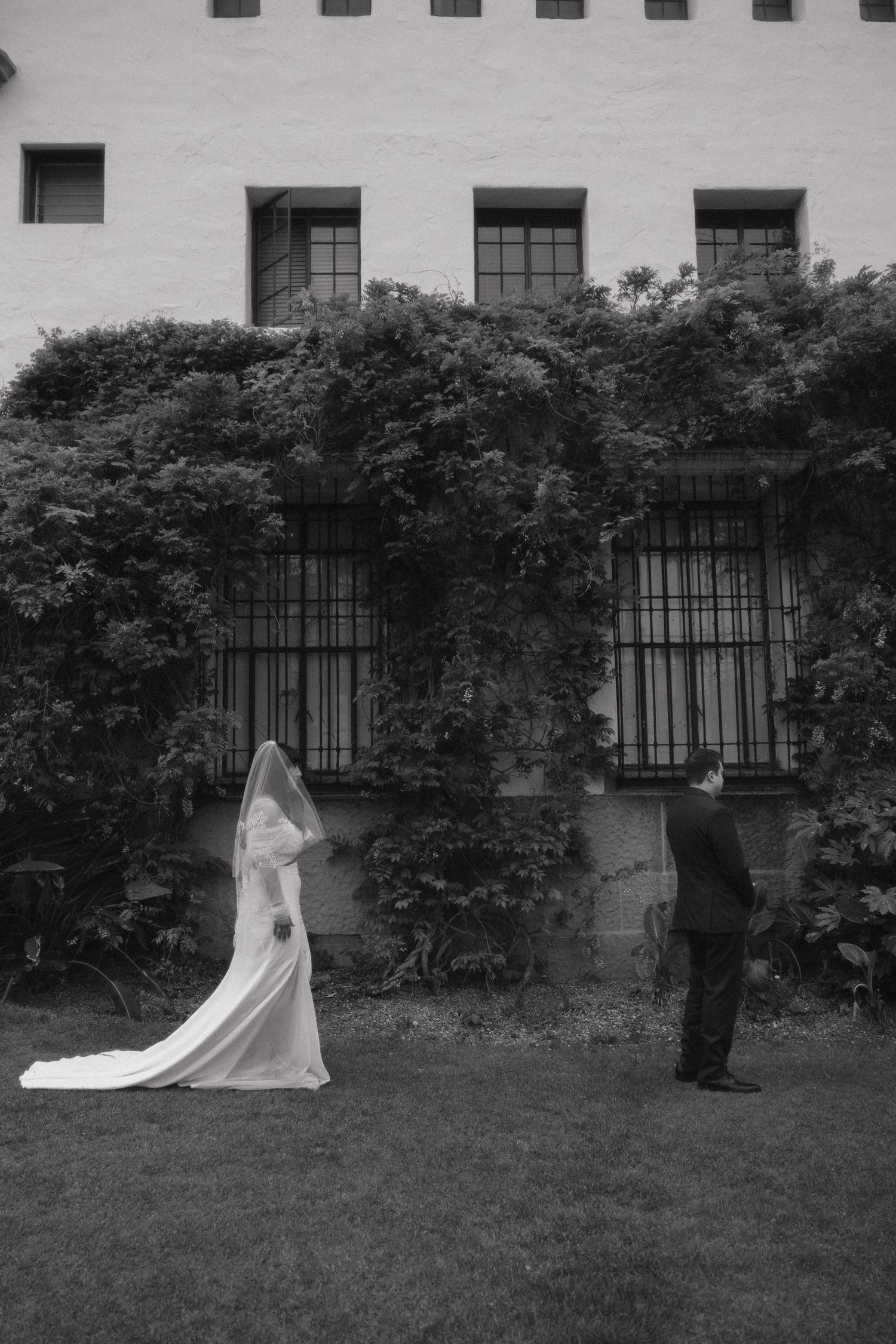 A sequence of black and white photos showing a person in a dark coat approaching a ghostly white figure in a garden.