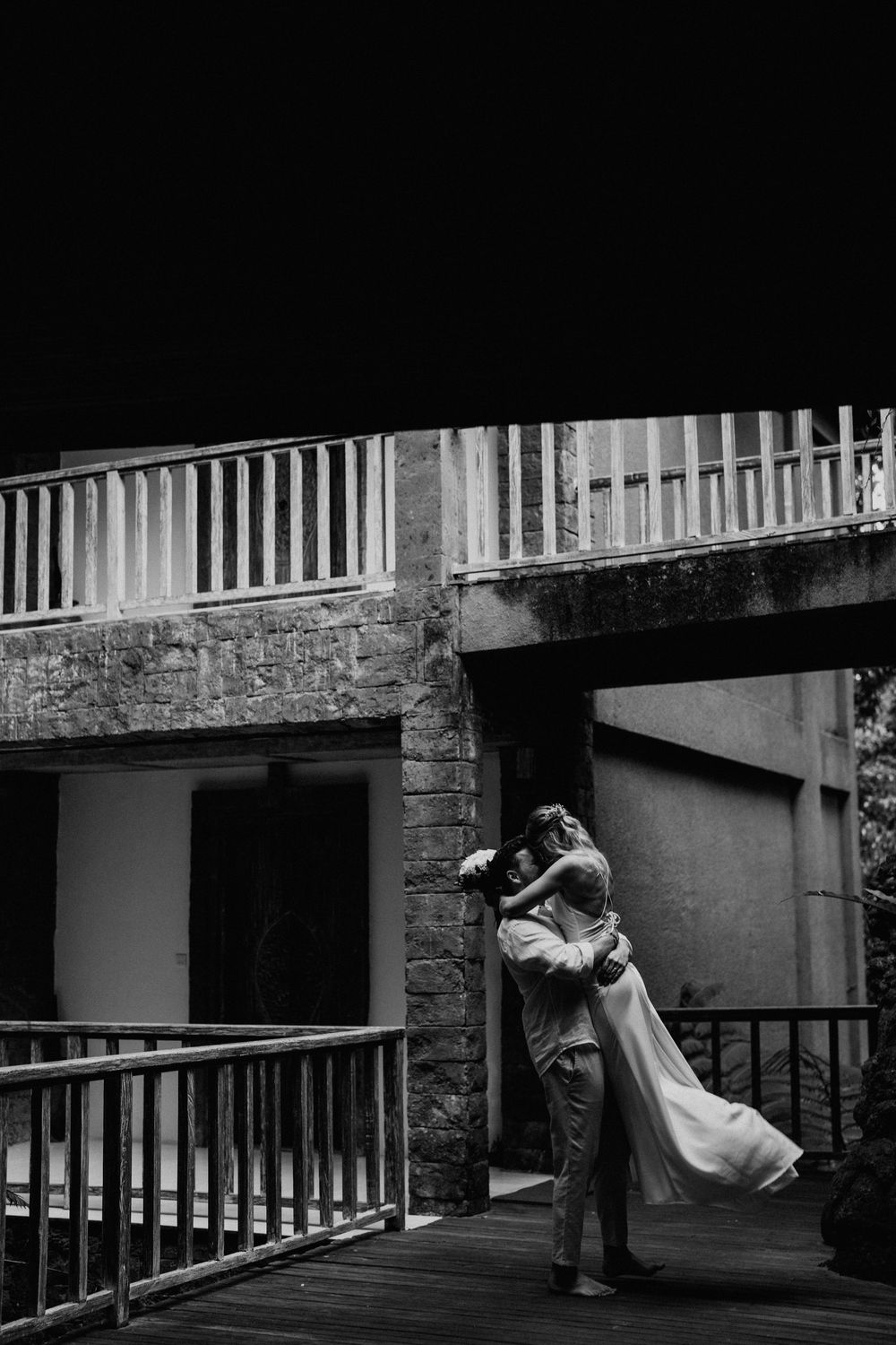 Dramatic black and white wedding sequence on a balcony with architectural details.