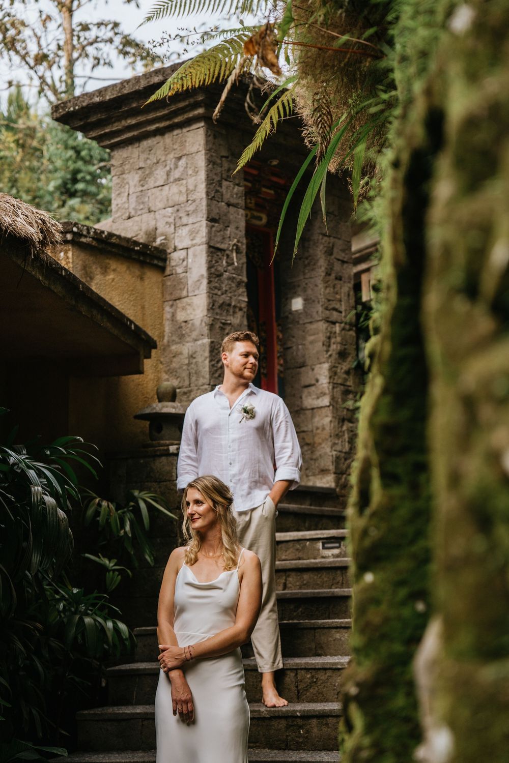 Stone staircase in tropical garden creates romantic backdrop for wedding photos.