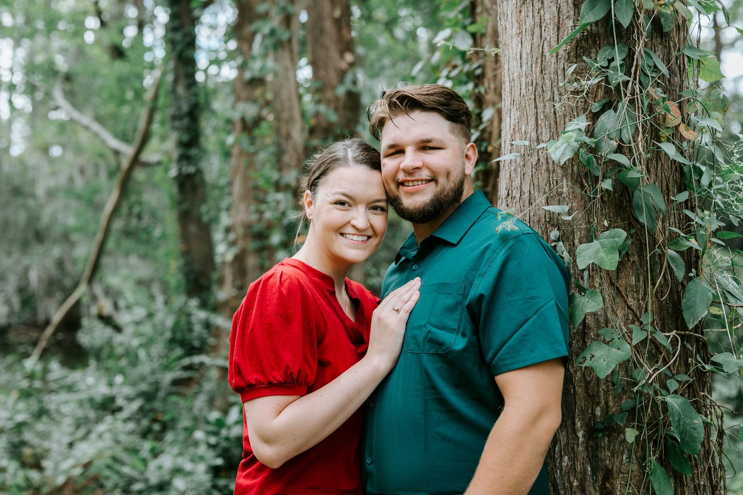 Loving couple embraces in a lush green forest setting during a romantic outdoor photo session.
