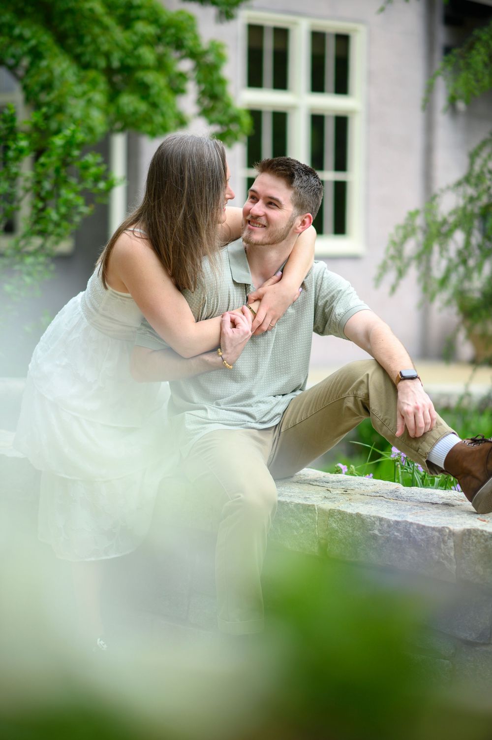 Intimate outdoor moment captured with soft focus and green foliage framing the scene.