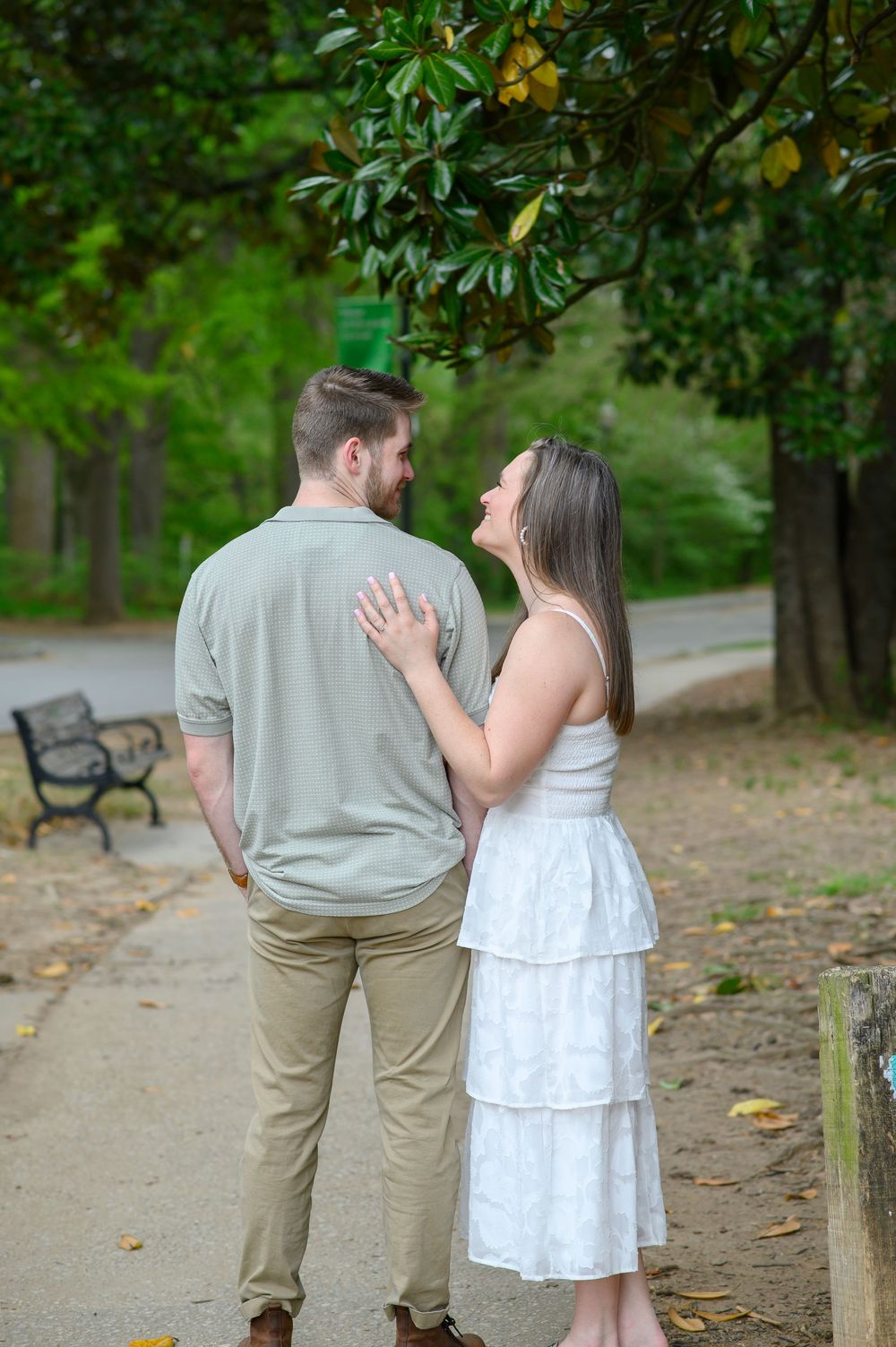 A couple shares an intimate moment while walking together in a lush green park on a beautiful summer day.