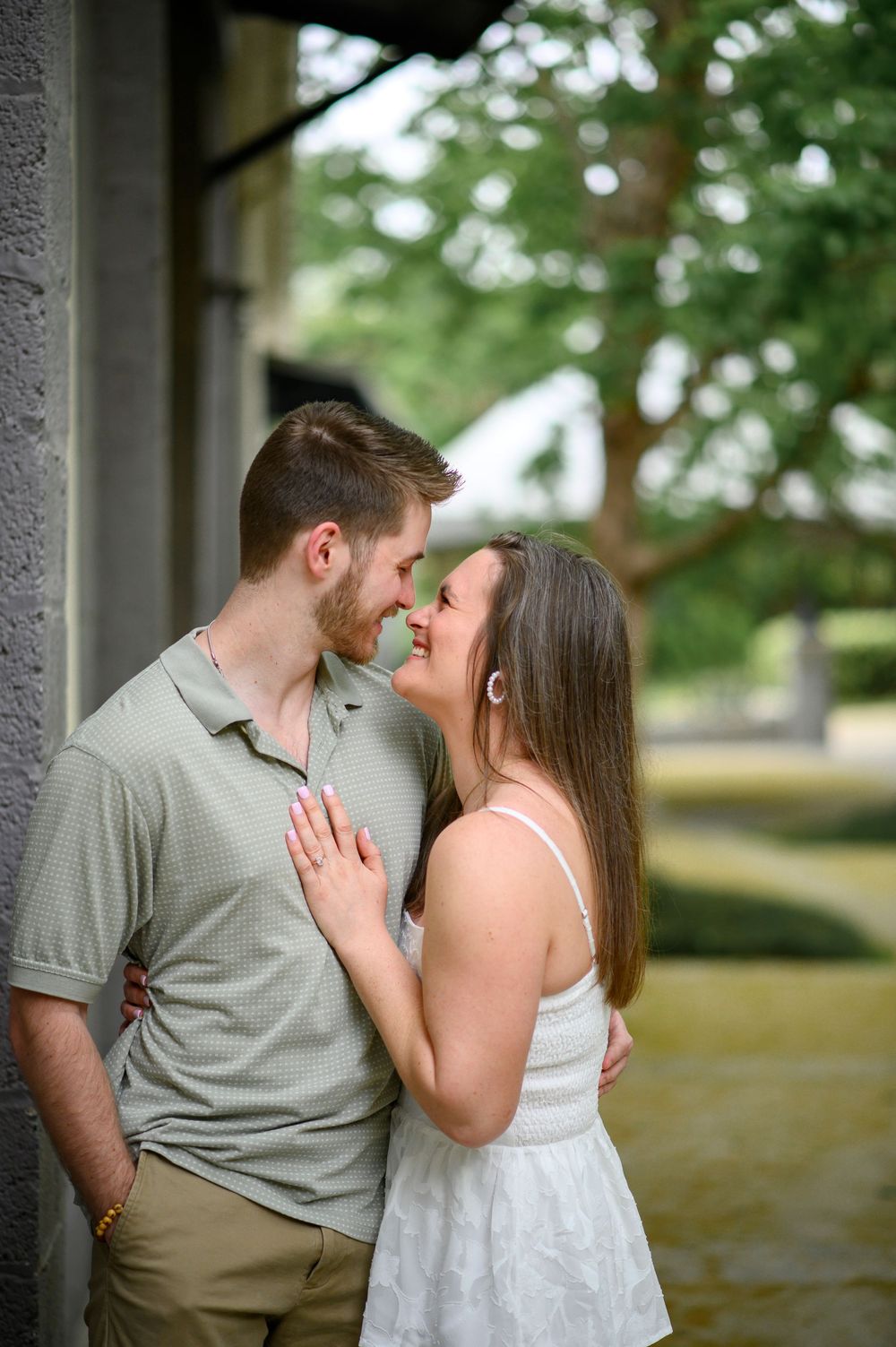 A romantic moment captured between a couple in an outdoor setting with greenery in the background.