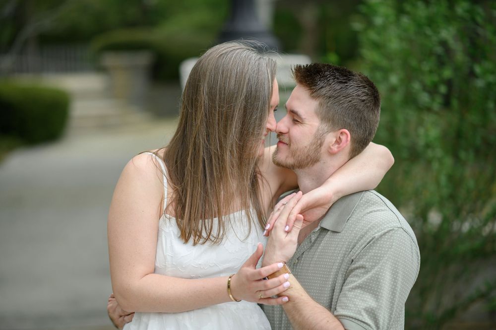 Couple sharing a romantic moment on a stone wall in a garden setting with lush greenery.