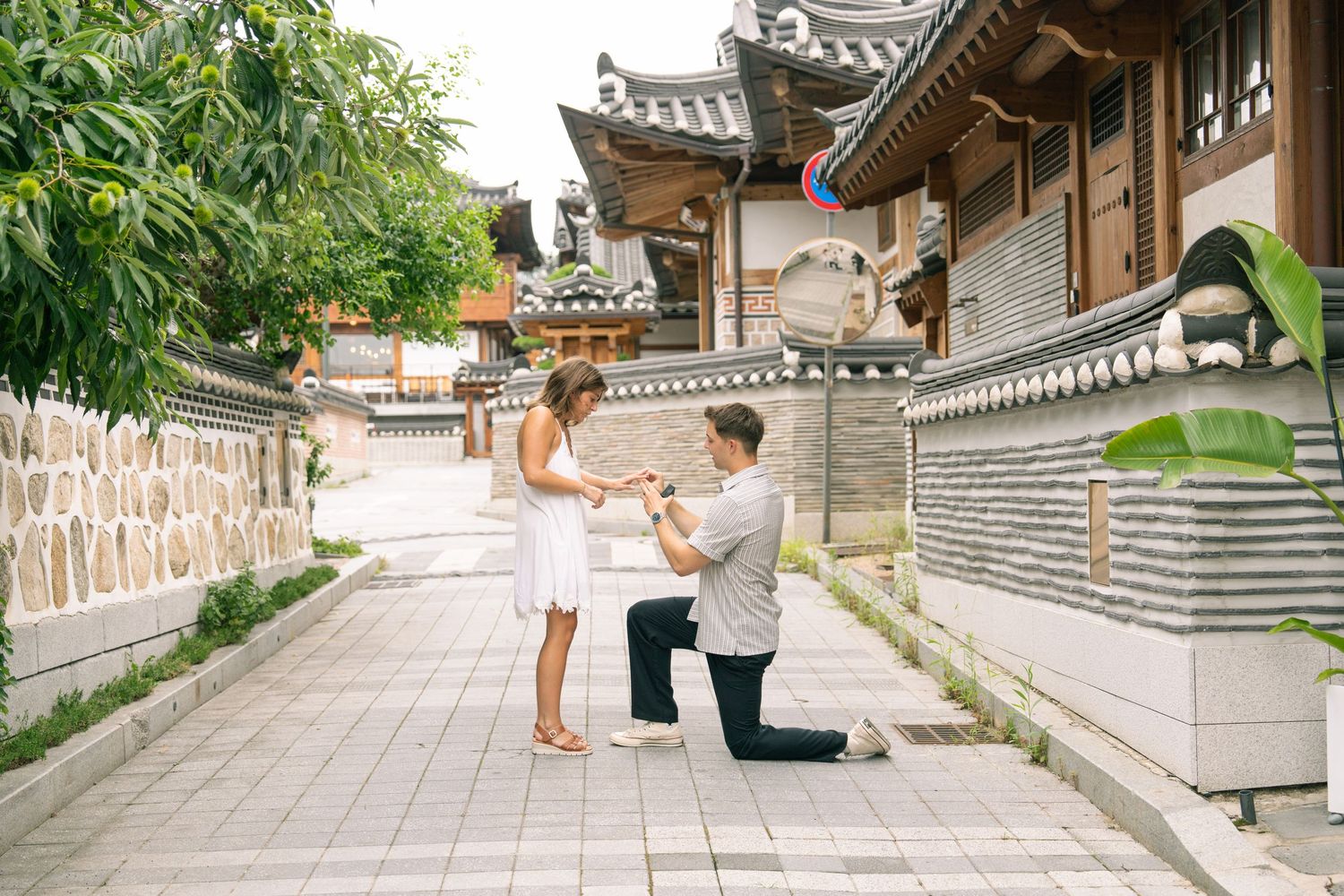 Young couple taking engagement photos at a traditional Korean hanok village in traditional dress.