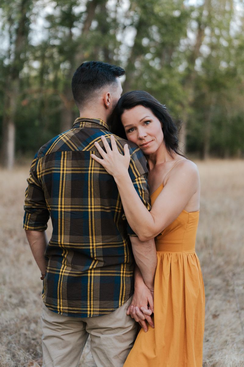 Romantic couple in outdoor field setting with person wearing plaid shirt and yellow sundress during couple photoshoot in Sydney Parkland