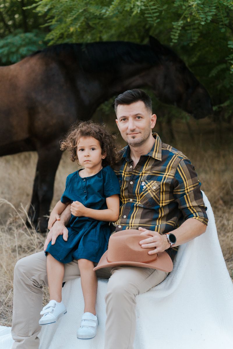 moments between father and child sitting on blanket in natural outdoor setting with a horse in the background family photoshoot Sydney