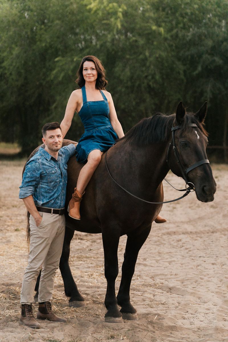 Photos of a loving moment between two people and a majestic black horse in a natural outdoor setting during a Sydney horse photoshoot