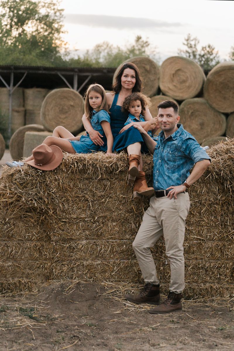 a family sitting together on hay bales in matching blue outfits on a sunny afternoon during a family photoshoot in Western Sydney