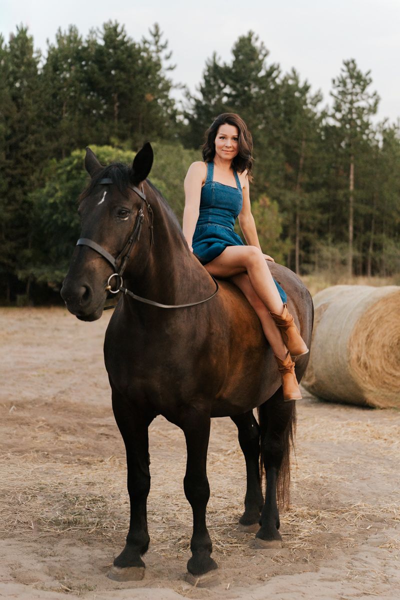 Woman in teal dress poses with beautiful dark horse against woodland backdrop in outdoor photoshoot in Sydney Hills