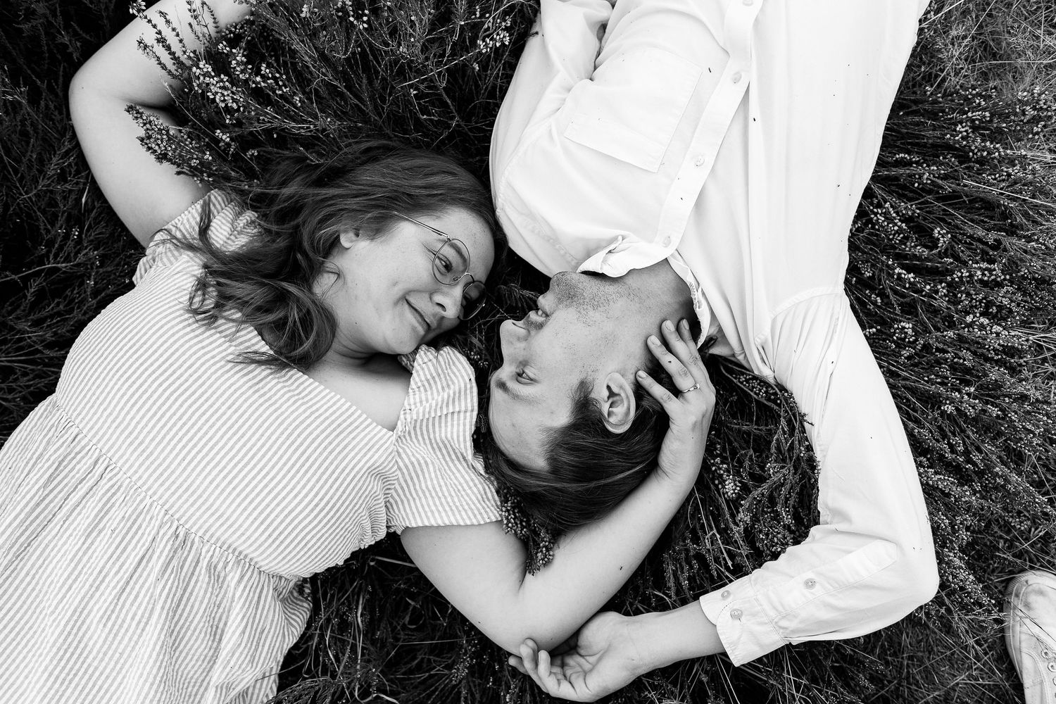 Black and white romantic sequence of couple lying in grass together.