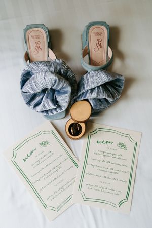 Wedding invitation cards with blue decorative bows and delicate green border details displayed on white surface.