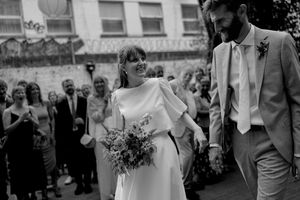 Wedding celebration outdoors with guests gathered around couple in classic black and white attire.