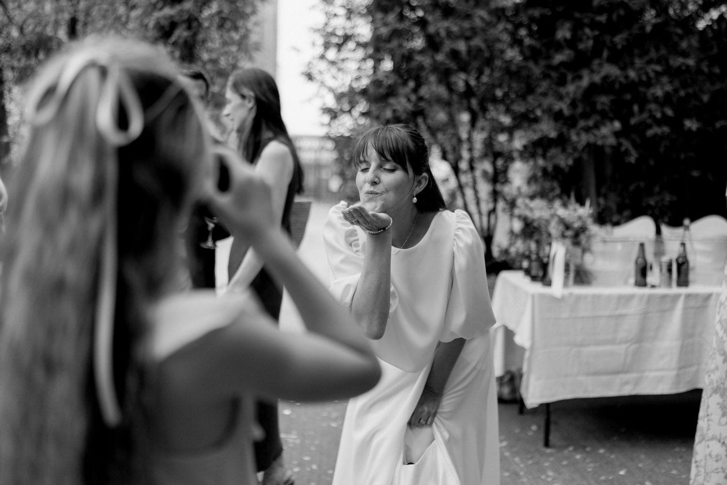 Wedding party members share candid moments outdoors in natural lighting.