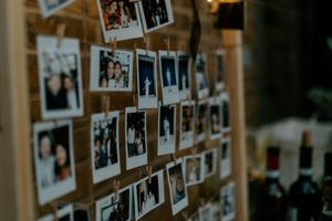 Multiple polaroid photos displayed on a wall creating a nostalgic memory collage in dim lighting.
