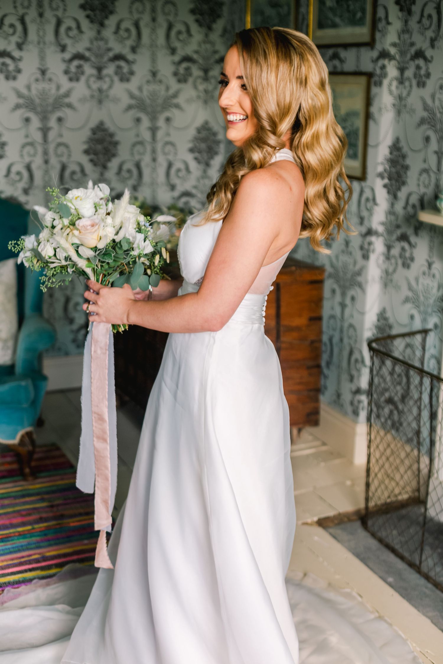 White wedding dress details in a room with damask wallpaper and colorful striped rug.