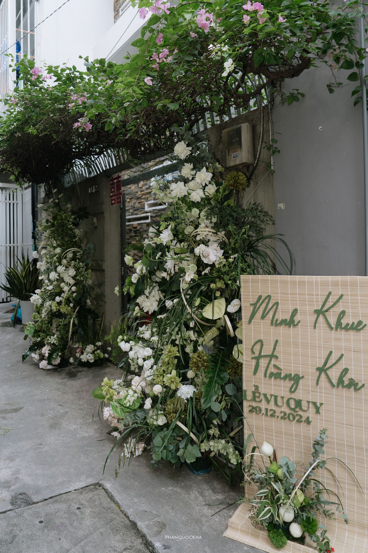 Elegant outdoor Vietnamese wedding entrance decorated with lush white floral arrangements and bamboo sign.