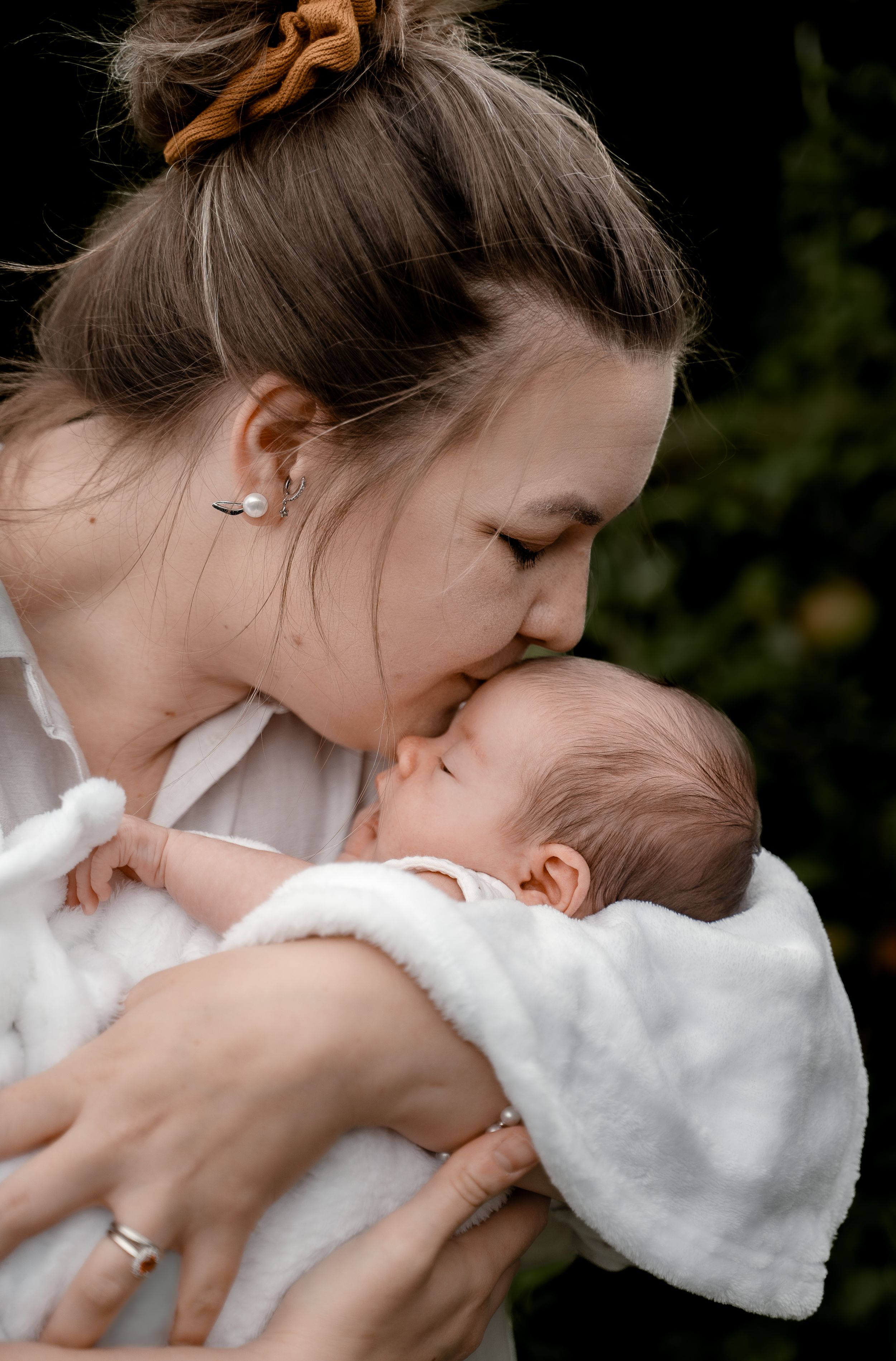 A tender moment between parent and newborn baby wrapped in soft white blanket.