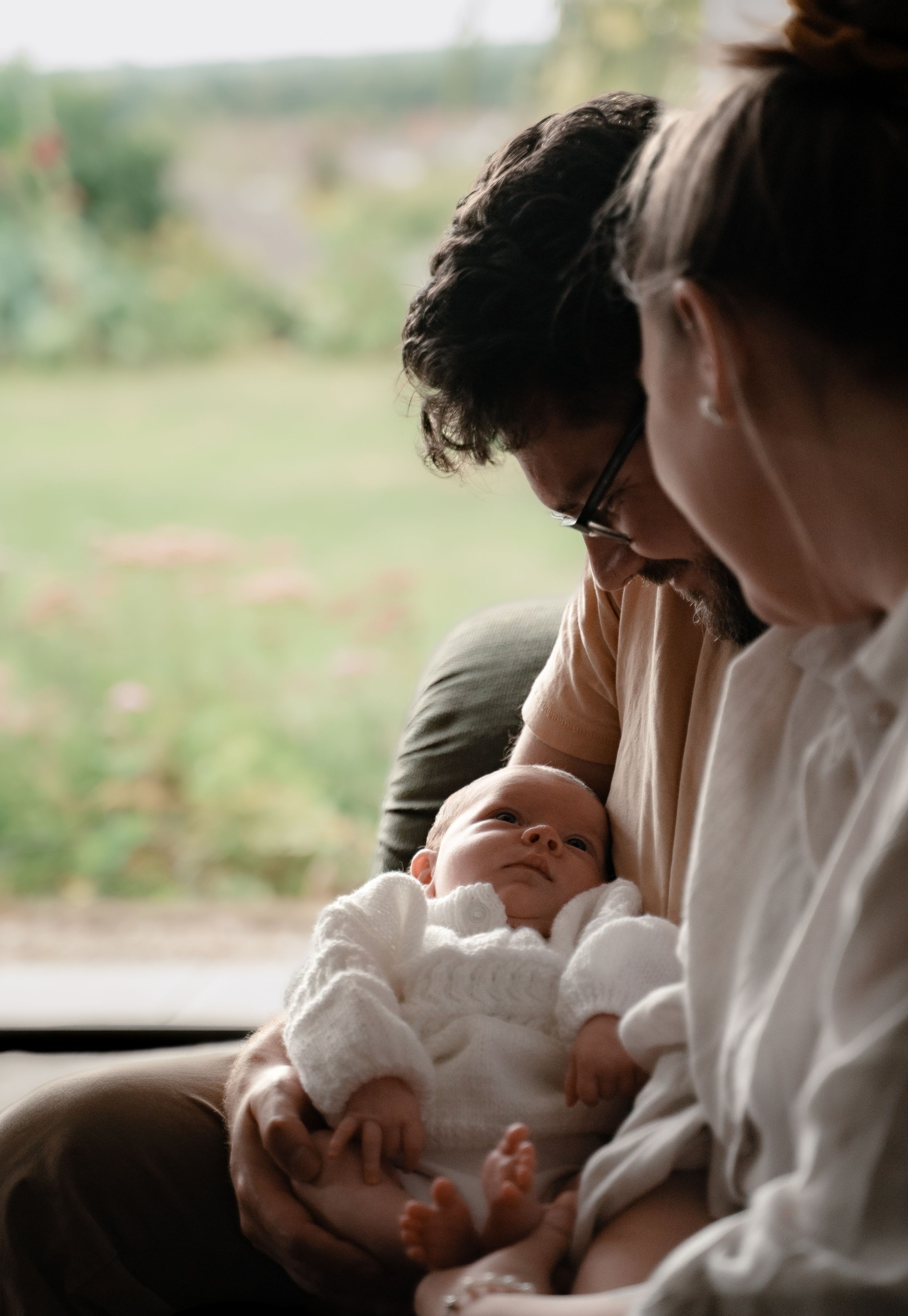A tender moment captured in a series of four connected images showing a parent cradling a newborn baby in soft natural light.