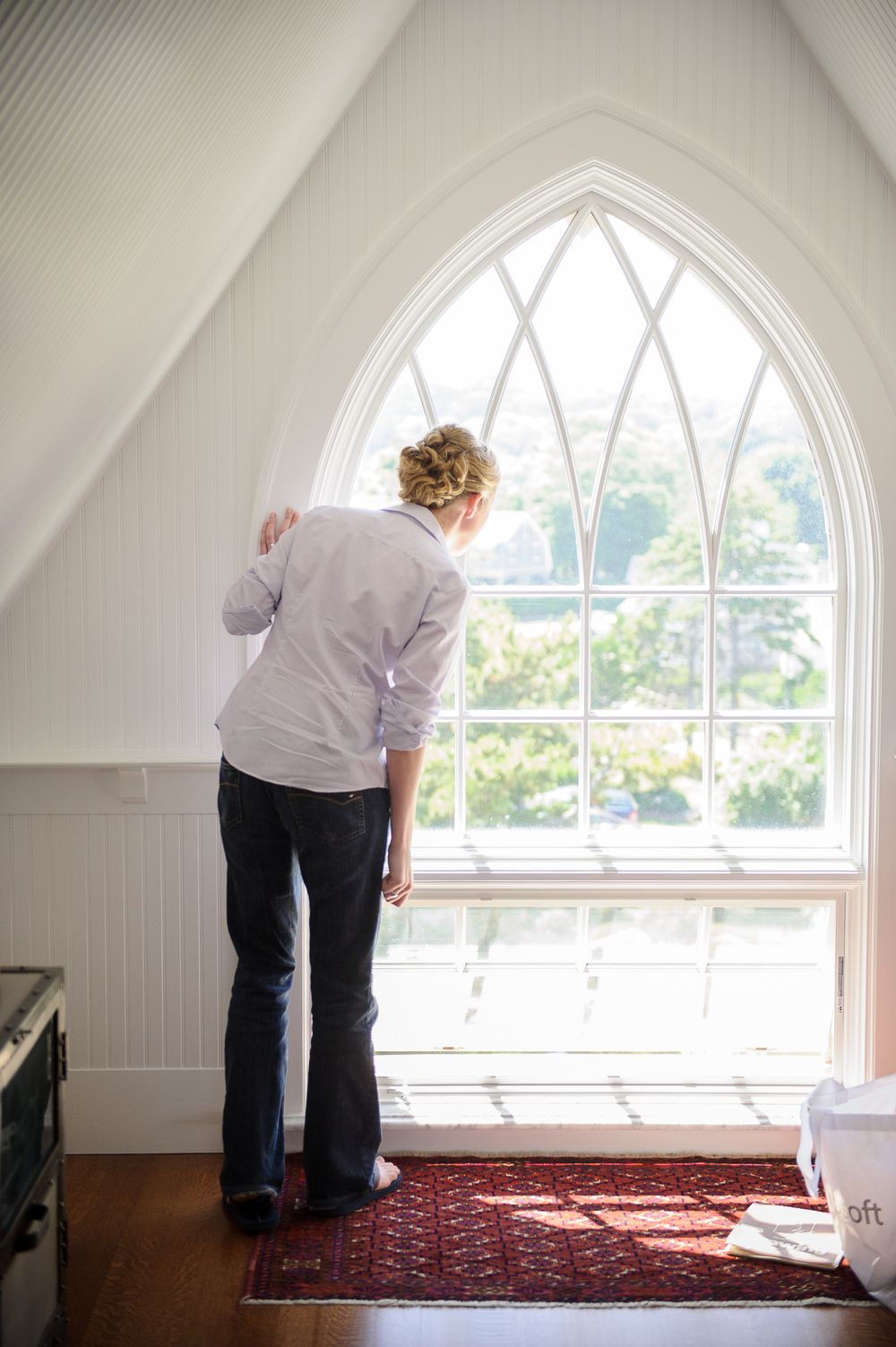 Series of photos showing someone looking out an arched window with white trim in an attic space.