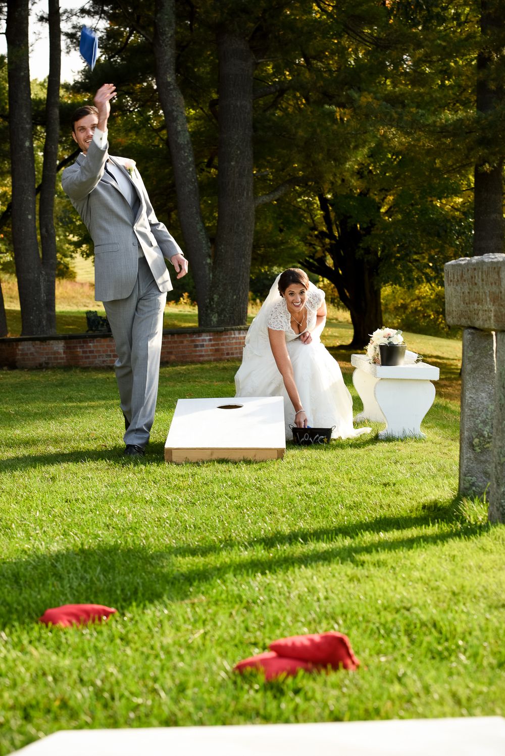 Guests enjoying outdoor lawn games and activities at an elegant wedding reception with red details.