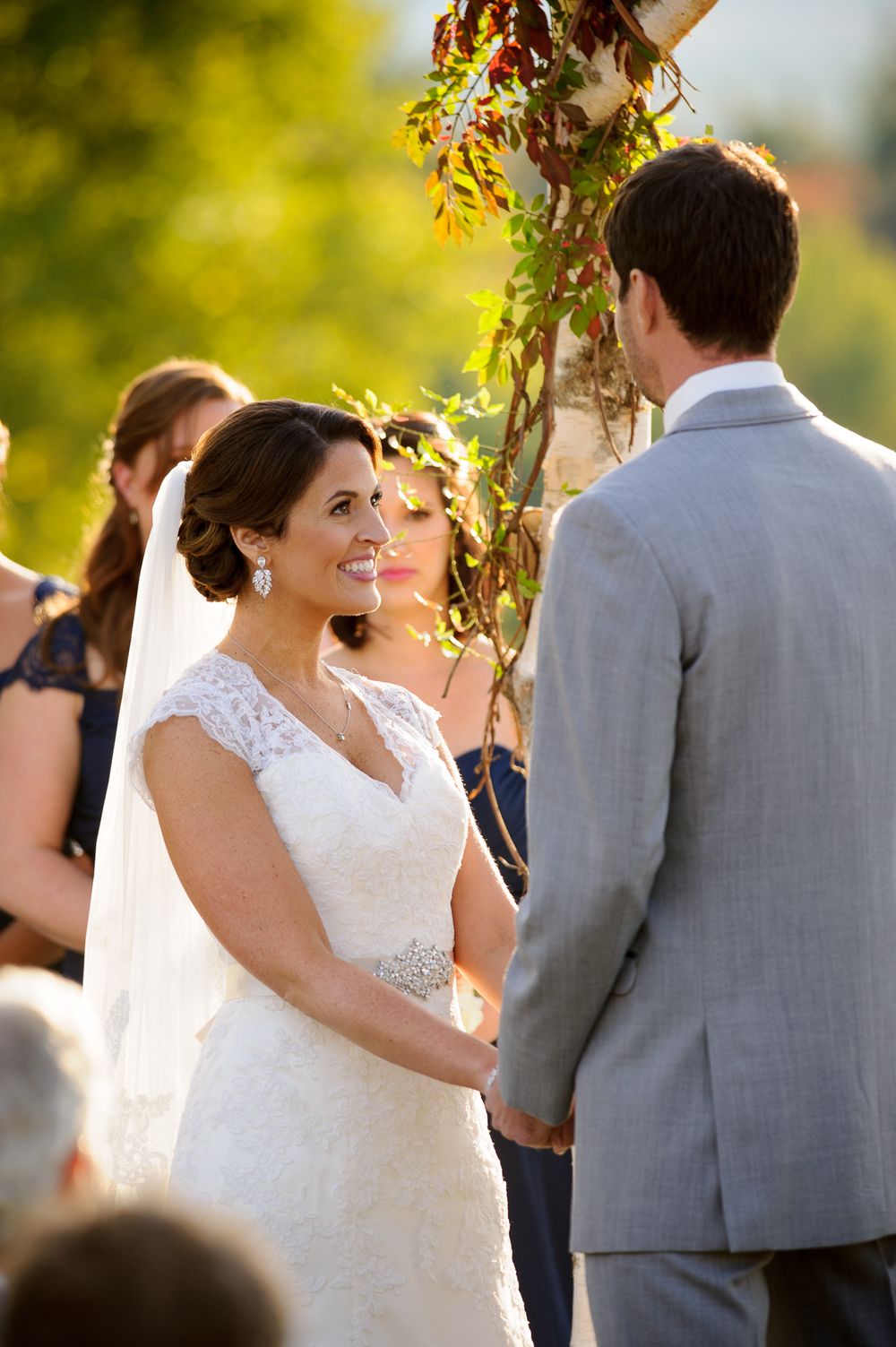 Happy couple shares a joyful moment during their outdoor wedding ceremony under golden sunlight and foliage.