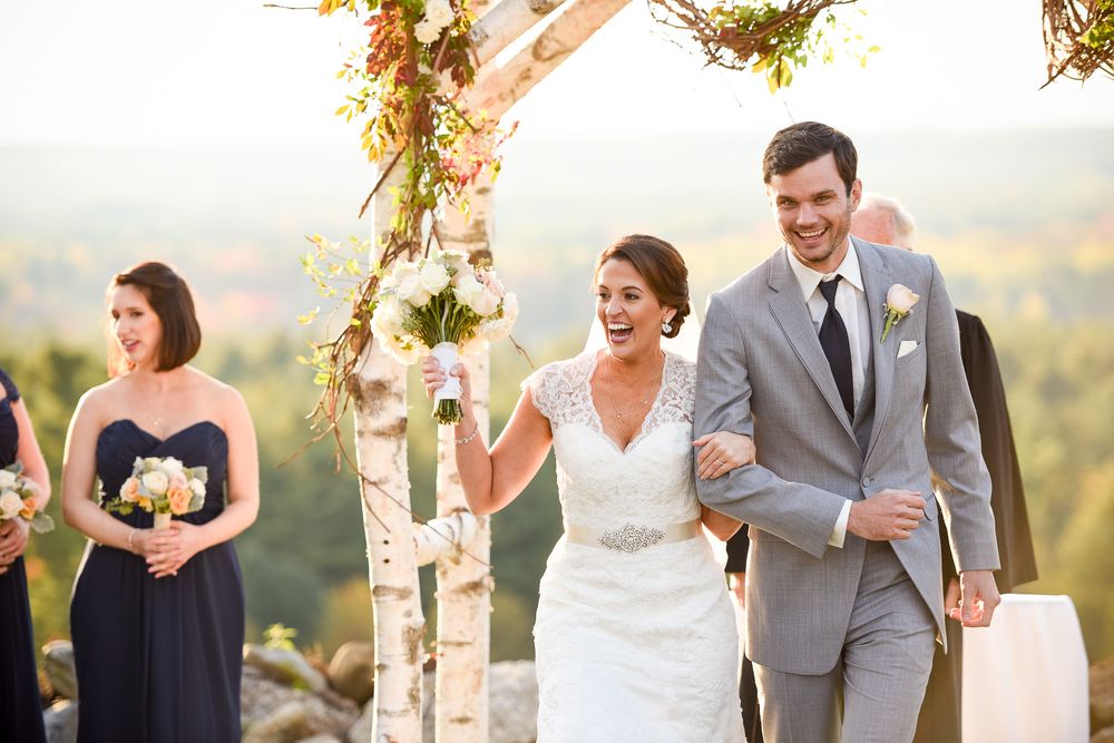 Wedding couple shares joyful moments at an outdoor ceremony with a scenic mountaintop view in the background.
