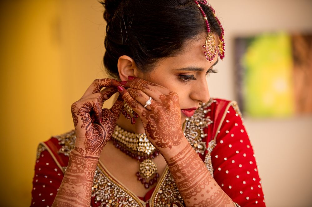 Traditional Indian bride wearing ornate gold jewelry and red attire during wedding preparations.