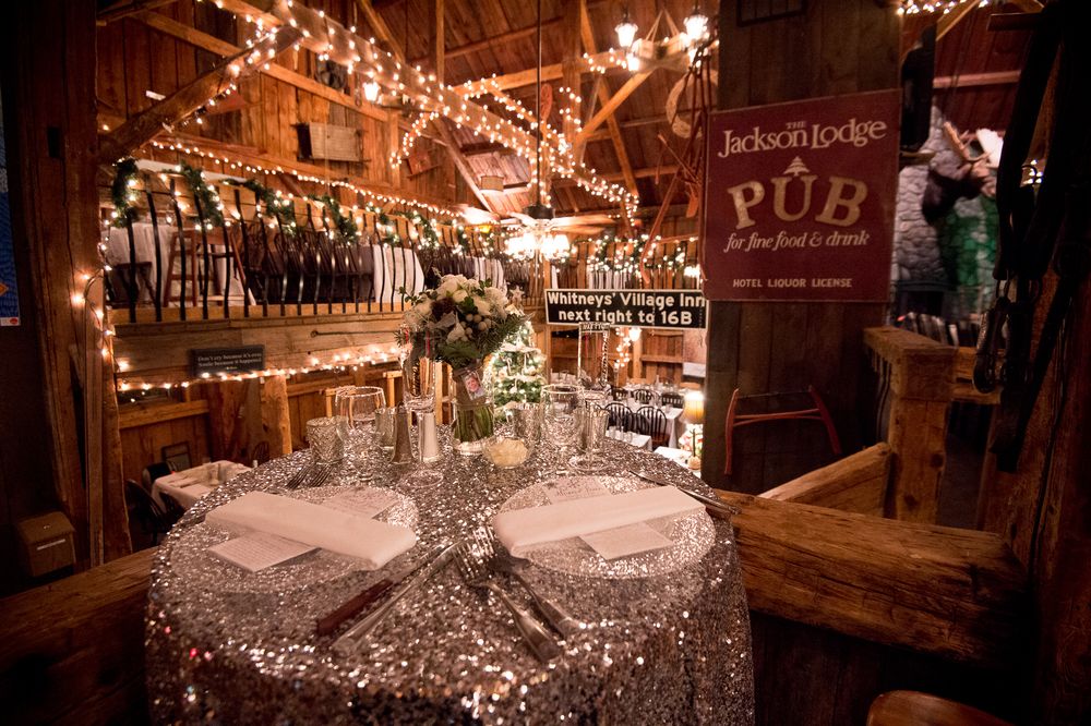 Rustic pub table decorated with sparkly sequin tablecloth and string lights for an intimate wedding reception setting.