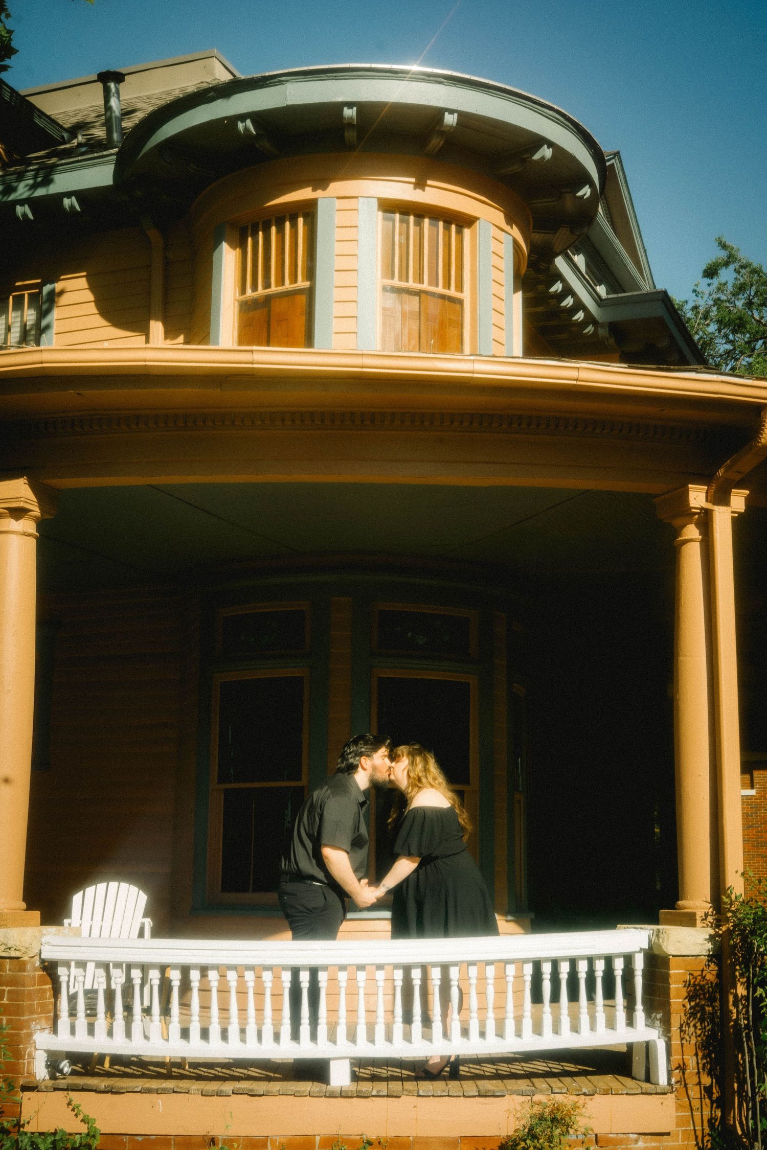Panoramic view of a craftsman style porch with white railings at sunset.