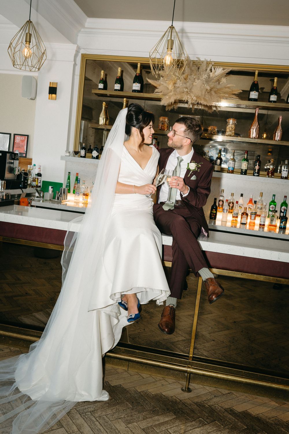 A couple shares a romantic dance together at a wedding reception near a wooden bar area. Taken by modern editorial wedding photographer.