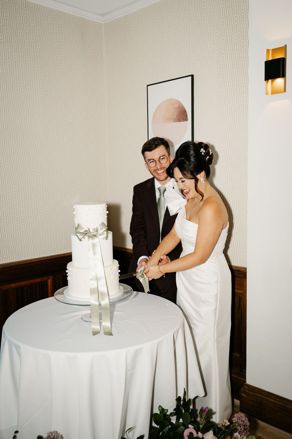 Candid moments of wedding cake cutting ceremony at an elegant indoor reception. Taken by modern editorial wedding photographer.