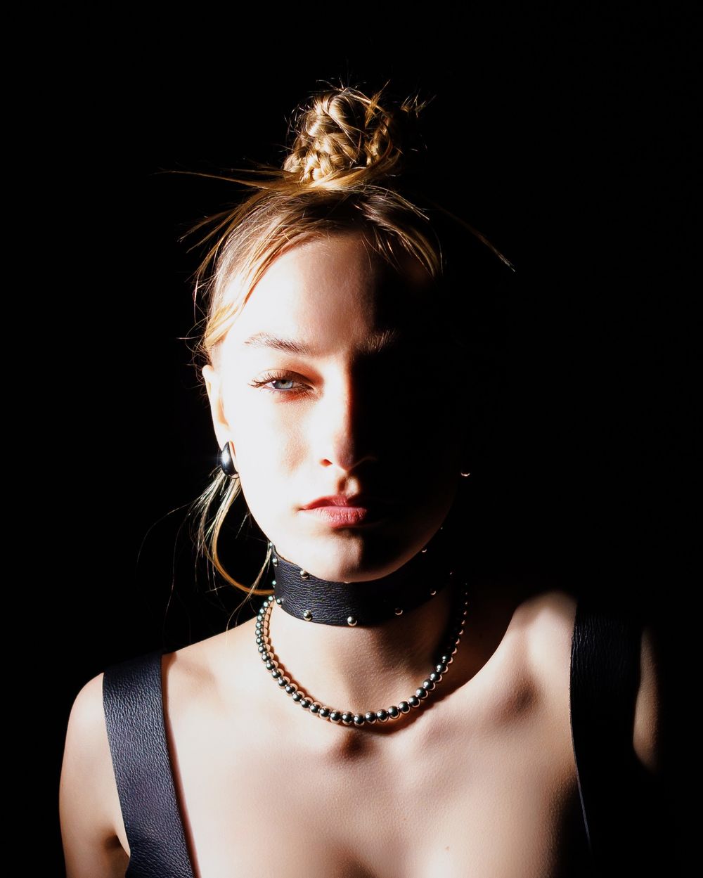 Dramatic artistic portrait series showcasing black choker necklace and earrings against dark background lighting.