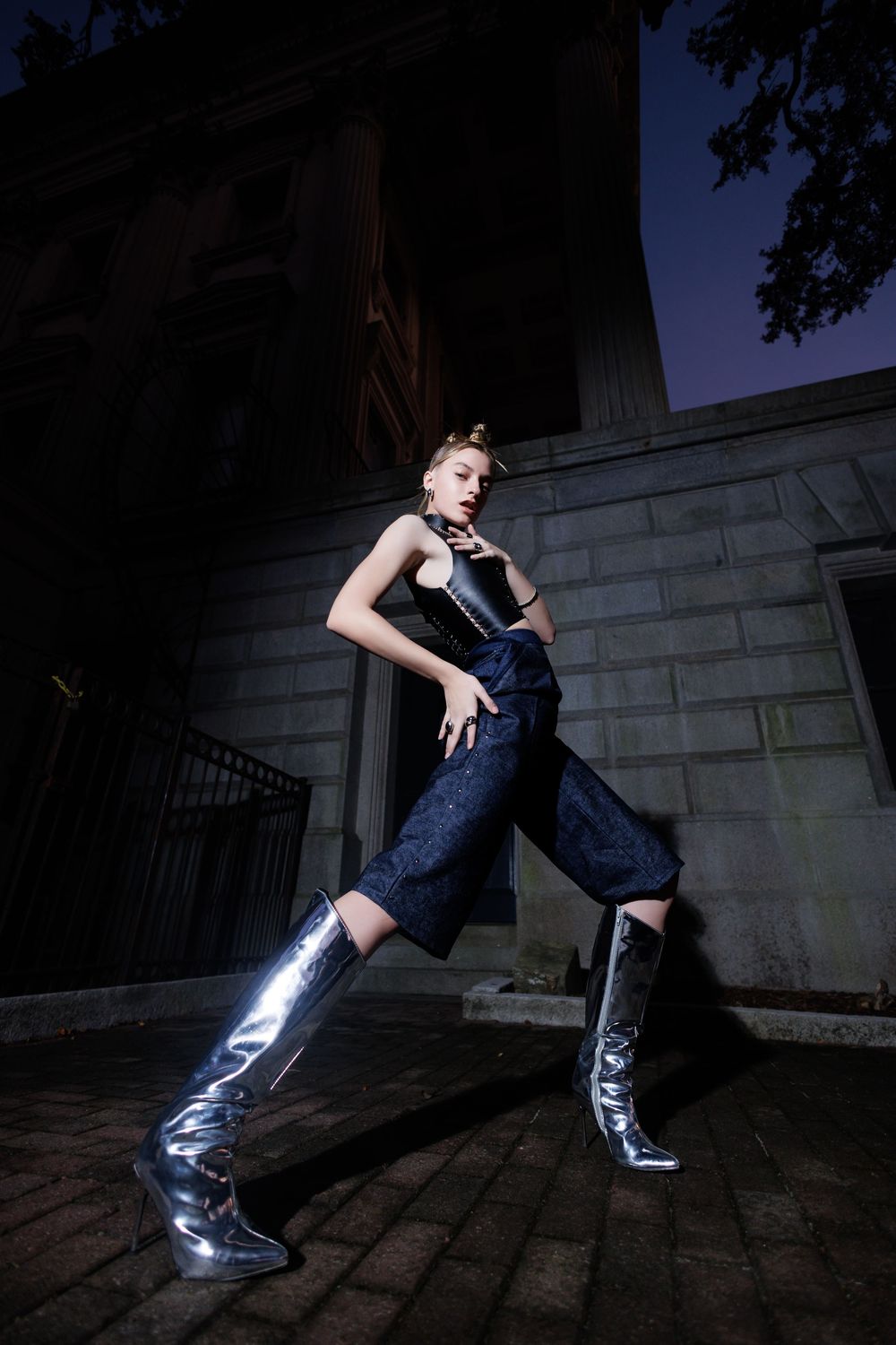 Four artistically composed photos of metallic boots against a dark stone wall in dramatic nighttime lighting.
